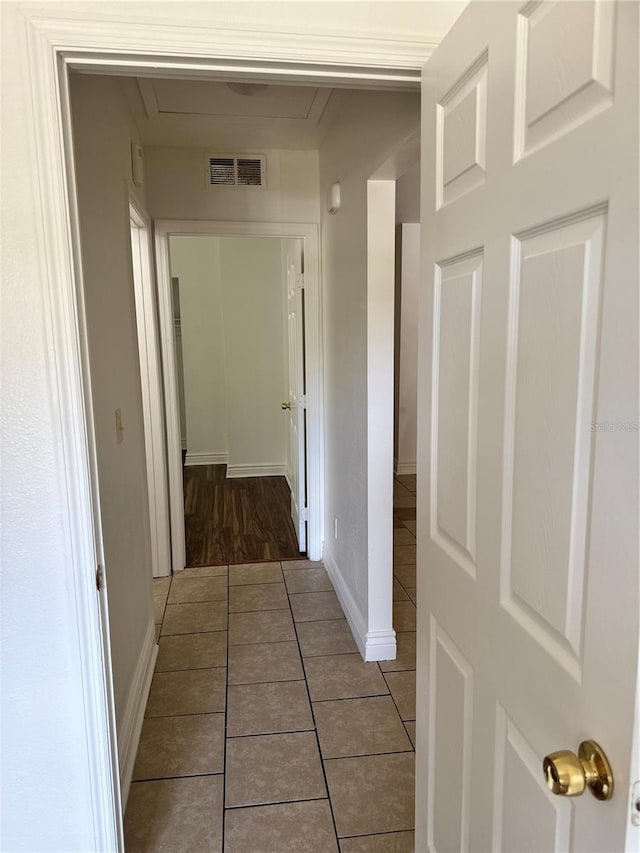 hallway featuring baseboards, visible vents, and tile patterned floors