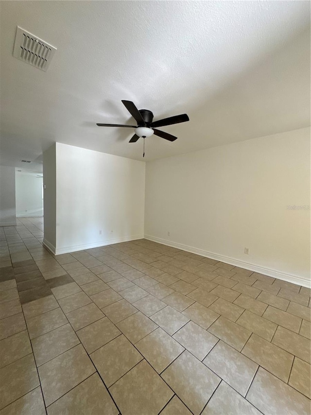 spare room featuring light tile patterned floors, visible vents, baseboards, ceiling fan, and a textured ceiling