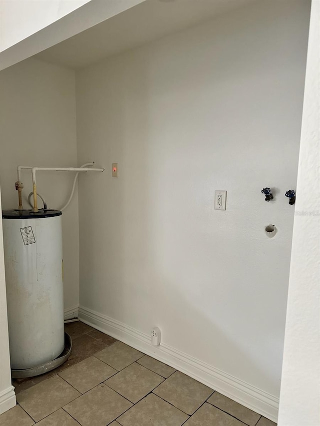 washroom with gas water heater, hookup for a washing machine, tile patterned flooring, laundry area, and baseboards