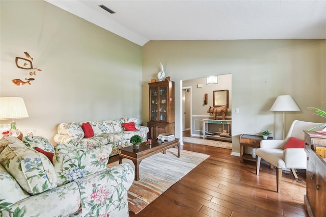 living area with lofted ceiling, dark wood finished floors, and visible vents