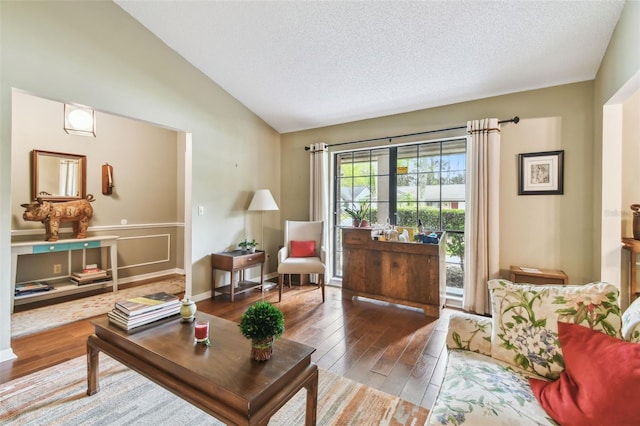 living area with lofted ceiling, a textured ceiling, and wood finished floors