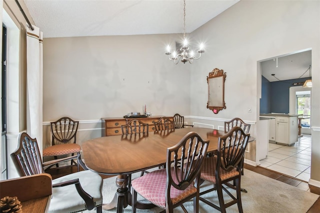 dining area with lofted ceiling, light wood-type flooring, and a notable chandelier