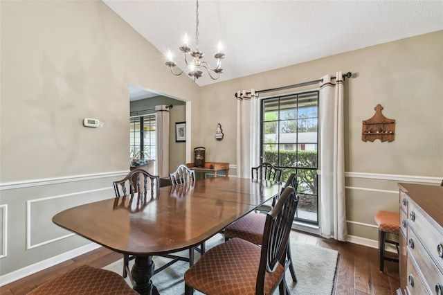 dining area featuring vaulted ceiling, dark wood-type flooring, a chandelier, and baseboards