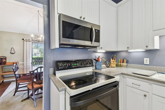 kitchen featuring white cabinetry, range with electric cooktop, stainless steel microwave, and light countertops