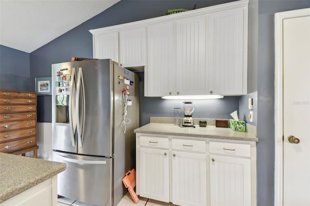 kitchen featuring lofted ceiling, light countertops, white cabinetry, and stainless steel fridge with ice dispenser