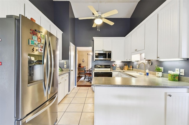 kitchen with appliances with stainless steel finishes, a peninsula, white cabinetry, a sink, and light tile patterned flooring