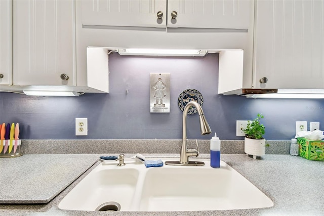 kitchen featuring light countertops, a sink, and white cabinets