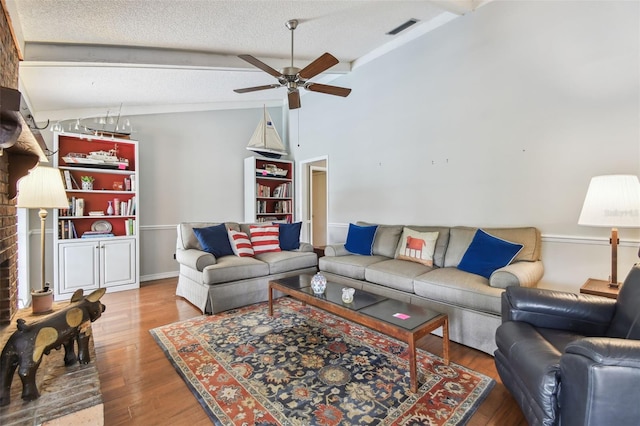 living area with vaulted ceiling with beams, visible vents, a ceiling fan, a textured ceiling, and wood finished floors