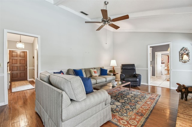 living area featuring visible vents, a ceiling fan, wood finished floors, beamed ceiling, and baseboards