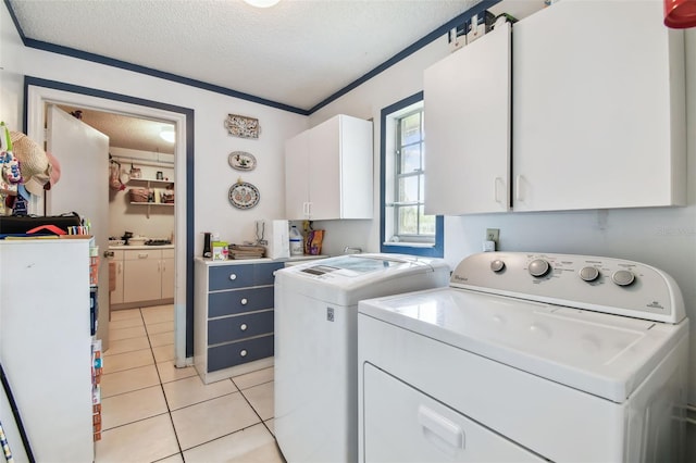 laundry area featuring light tile patterned floors, cabinet space, ornamental molding, washing machine and dryer, and a textured ceiling