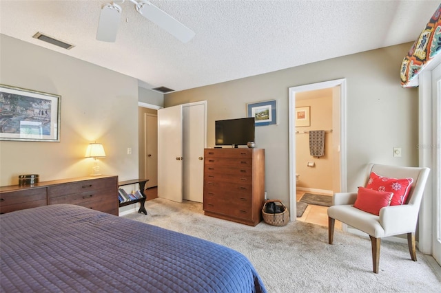 bedroom featuring visible vents, light colored carpet, a textured ceiling, and ensuite bathroom