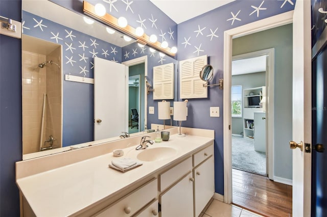 full bath with baseboards, vanity, and wallpapered walls