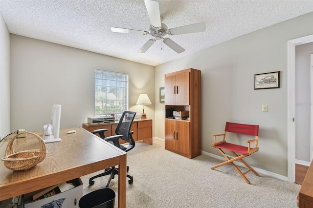 office featuring light carpet, ceiling fan, baseboards, and a textured ceiling