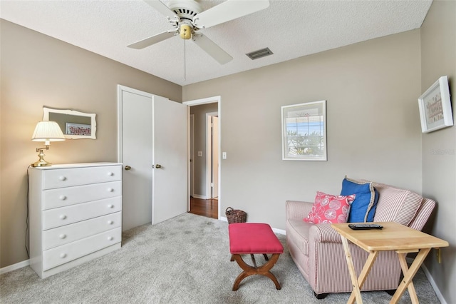 living area featuring a textured ceiling, ceiling fan, light carpet, and visible vents