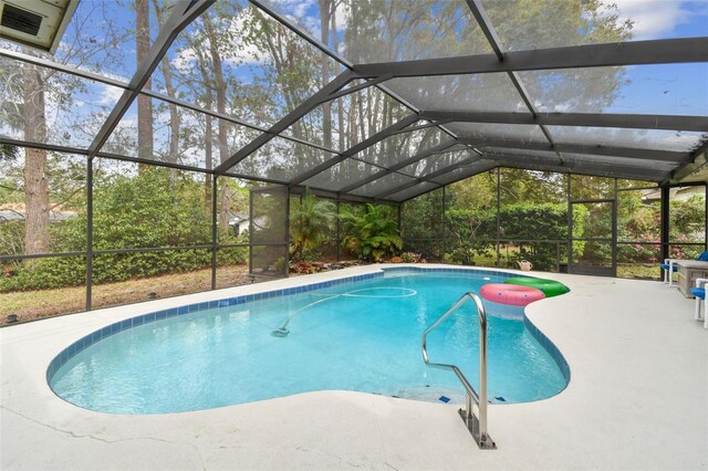 outdoor pool featuring glass enclosure and a patio