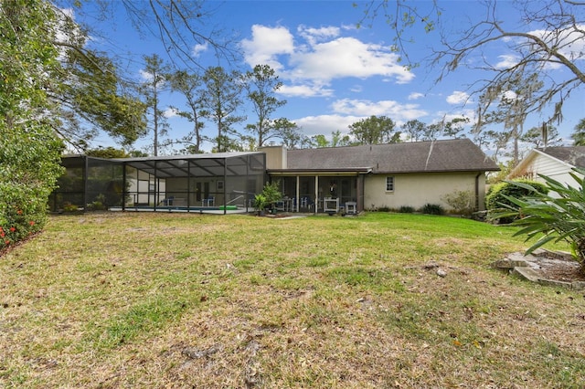 rear view of property with glass enclosure, stucco siding, and a yard