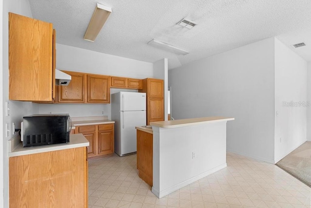 kitchen featuring light floors, visible vents, black microwave, and freestanding refrigerator