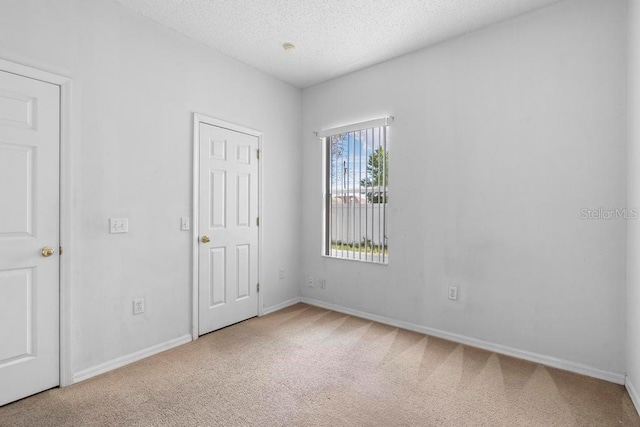 unfurnished bedroom with a textured ceiling, baseboards, and carpet flooring