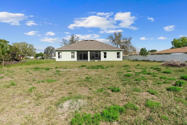 back of house with fence, a lawn, and stucco siding