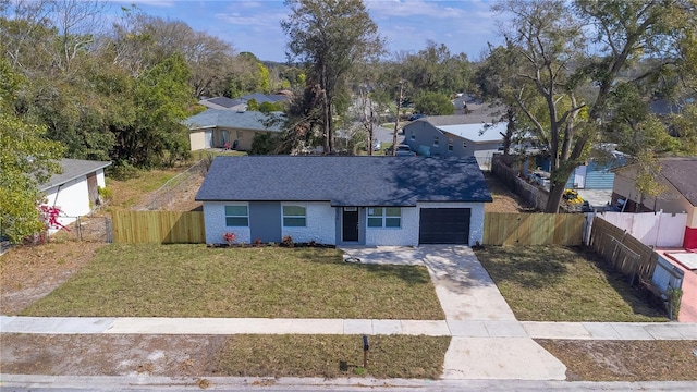 view of front of property with concrete driveway, a fenced backyard, an attached garage, and a front lawn