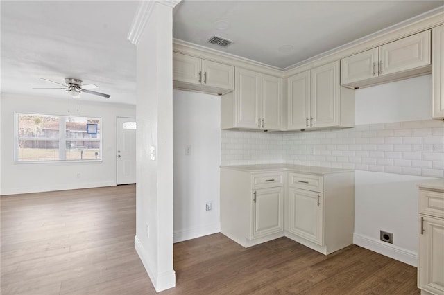 kitchen with dark wood-type flooring, a ceiling fan, visible vents, light countertops, and decorative backsplash