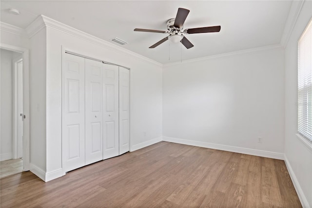 unfurnished bedroom featuring a closet, visible vents, light wood-style floors, ornamental molding, and baseboards