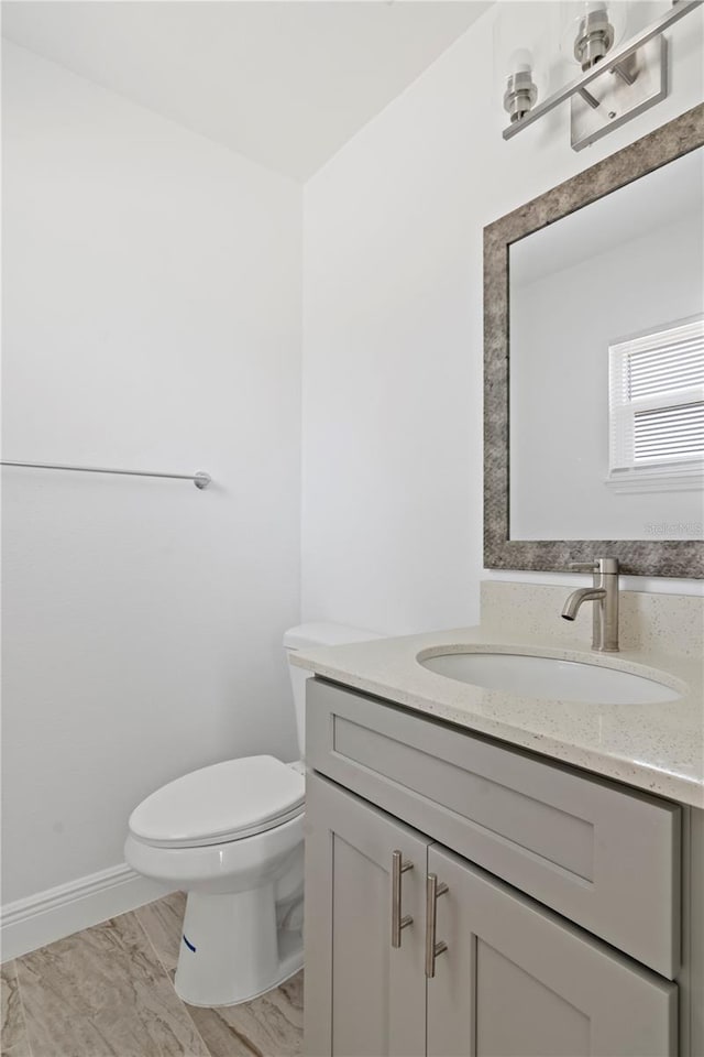 bathroom featuring toilet, vanity, and baseboards