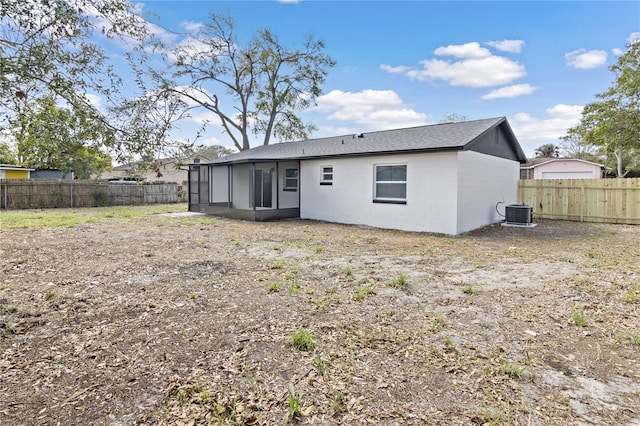 rear view of property featuring central AC unit, a sunroom, a fenced backyard, and concrete block siding