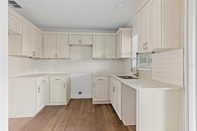 kitchen with light countertops, wood finished floors, a sink, and visible vents