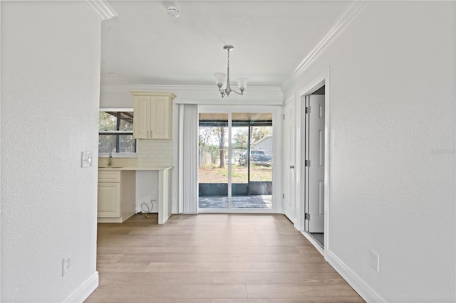 interior space with light wood finished floors, ornamental molding, a sink, and a healthy amount of sunlight