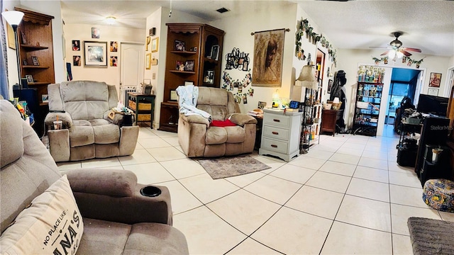 living area with ceiling fan, a textured ceiling, and light tile patterned floors