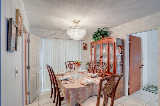 dining room with an inviting chandelier, light tile patterned floors, and a textured ceiling