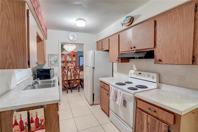 kitchen featuring white appliances, tasteful backsplash, light countertops, under cabinet range hood, and light tile patterned flooring