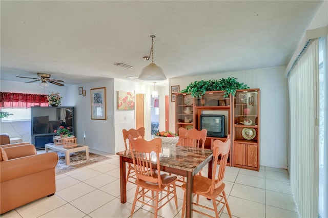 dining area featuring a ceiling fan, a glass covered fireplace, visible vents, and light tile patterned floors