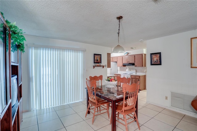 dining room with a textured ceiling, light tile patterned flooring, and visible vents