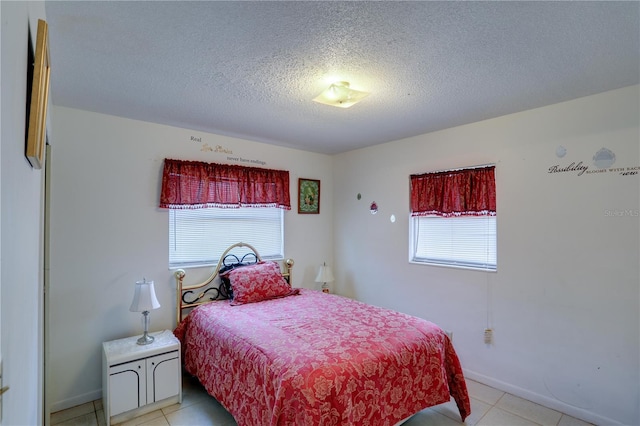 bedroom with multiple windows, a textured ceiling, and light tile patterned floors