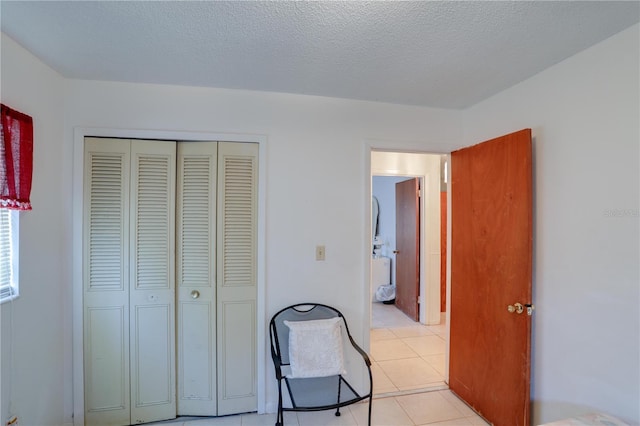 bedroom with a closet, light tile patterned flooring, and a textured ceiling