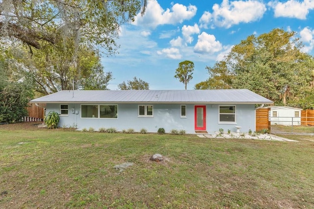 single story home with metal roof, a front lawn, and fence