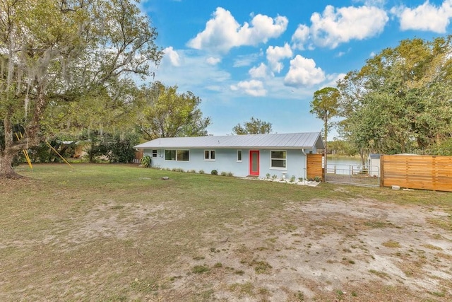 view of front of property featuring metal roof, a front yard, and fence