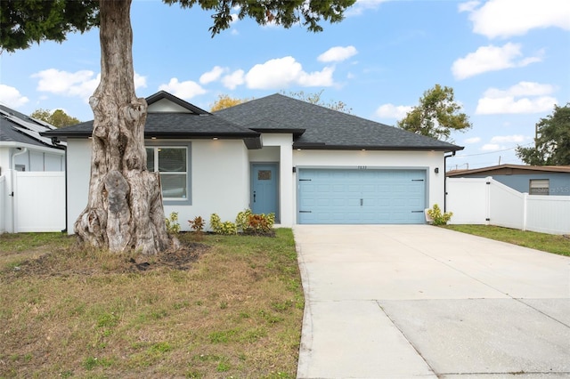 view of front of home with driveway, an attached garage, fence, a front lawn, and stucco siding