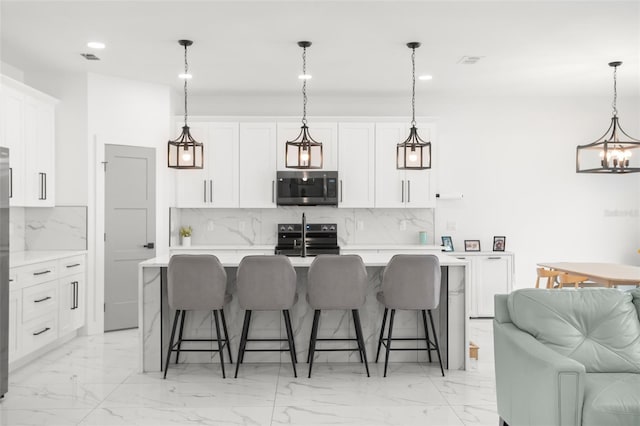 kitchen featuring a center island with sink, stainless steel appliances, backsplash, and light countertops