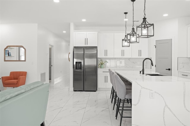 kitchen with light stone countertops, recessed lighting, marble finish floor, decorative backsplash, and stainless steel fridge