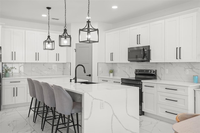 kitchen featuring marble finish floor, appliances with stainless steel finishes, an island with sink, and a sink