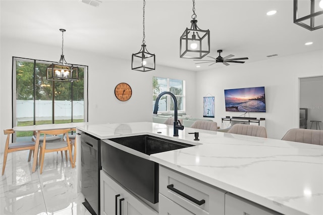 kitchen with recessed lighting, a sink, open floor plan, stainless steel dishwasher, and light stone countertops