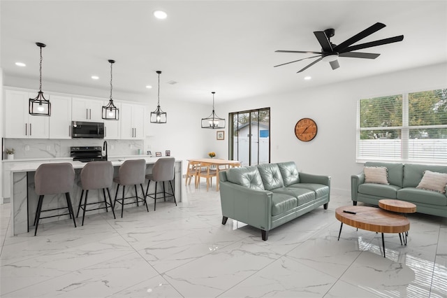 living room with marble finish floor, plenty of natural light, a ceiling fan, and recessed lighting