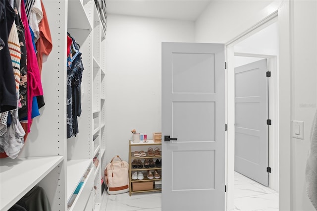 walk in closet featuring marble finish floor