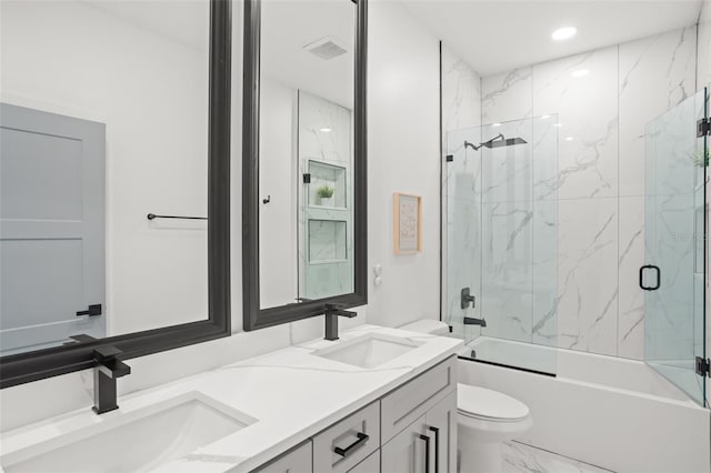 bathroom featuring marble finish floor, a sink, toilet, and double vanity