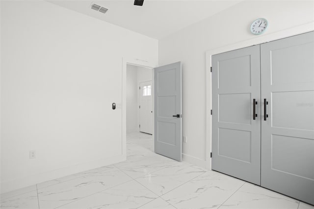 unfurnished bedroom featuring marble finish floor, a closet, visible vents, and baseboards