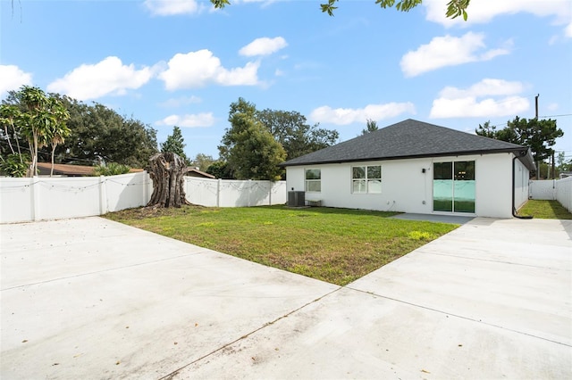 rear view of house featuring cooling unit, a fenced backyard, roof with shingles, a lawn, and a gate