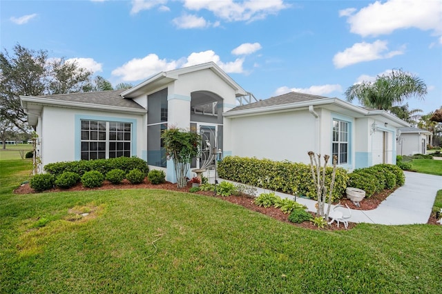 ranch-style home with stucco siding, driveway, a garage, and a front yard